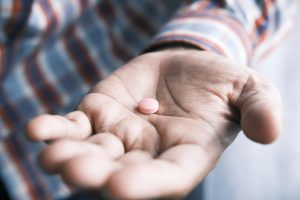 hand holding a pink pill