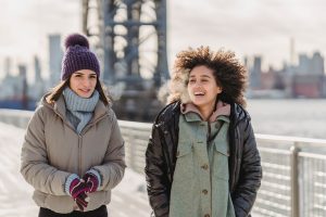 two women walking in winter under a bridge