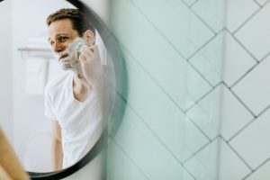 man looking in mirror while shaving
