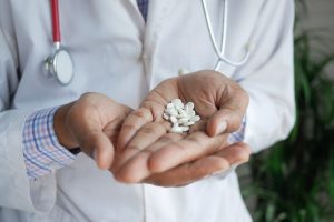 doctor holding several white pills