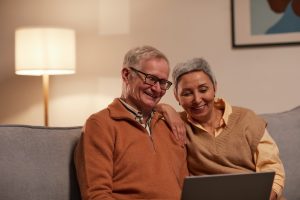 older couple sitting on the couch with laptop