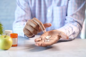 man counting pills in the palm of his hand