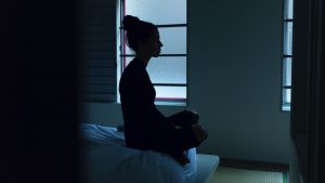 woman sitting on bed in dark room