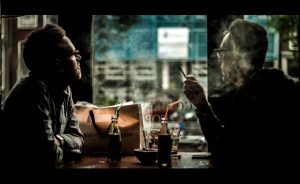 two men smoking marijuana in a cafe