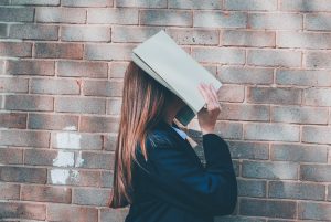 woman holding book over her face