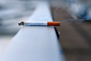 burning cigarette balanced on railing