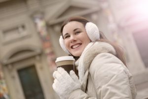 smiling woman in winter clothes holding a warm beverage