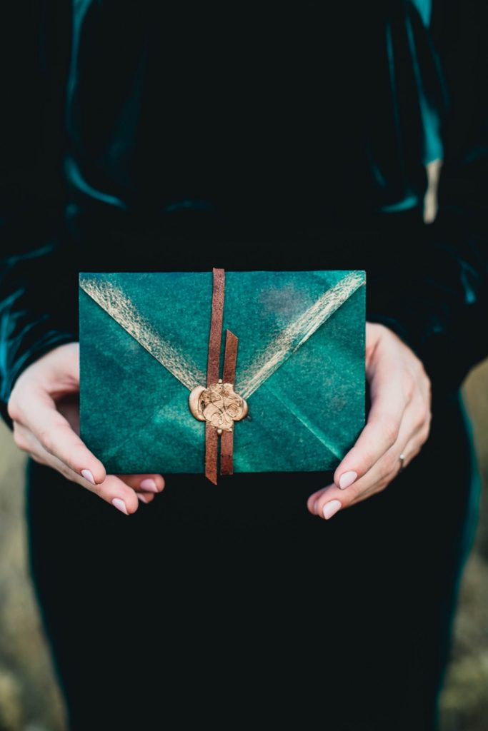 person holding blue-green gift envelope