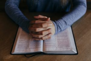 folded hands over a religious book