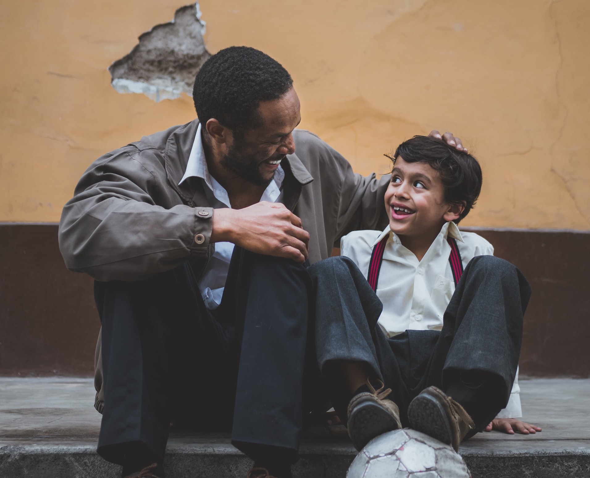 man talking to boy sitting on a curb