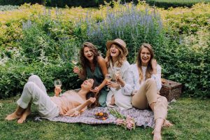 group of women having a picnic drinking wine laughing