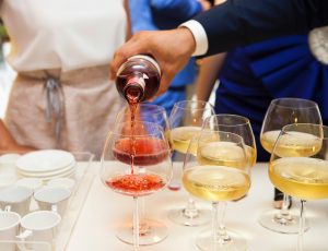 waiter pouring wine into several glasses