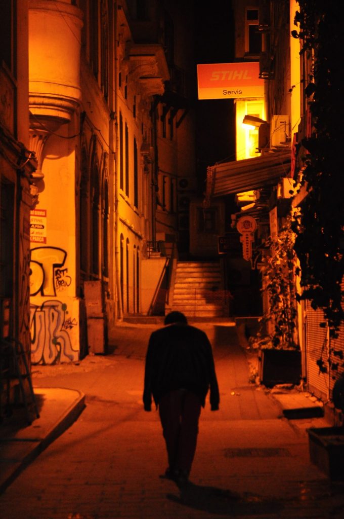 man in black coat walking down abandoned street