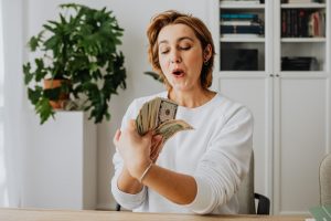 surprised looking woman holding a stack of dollars
