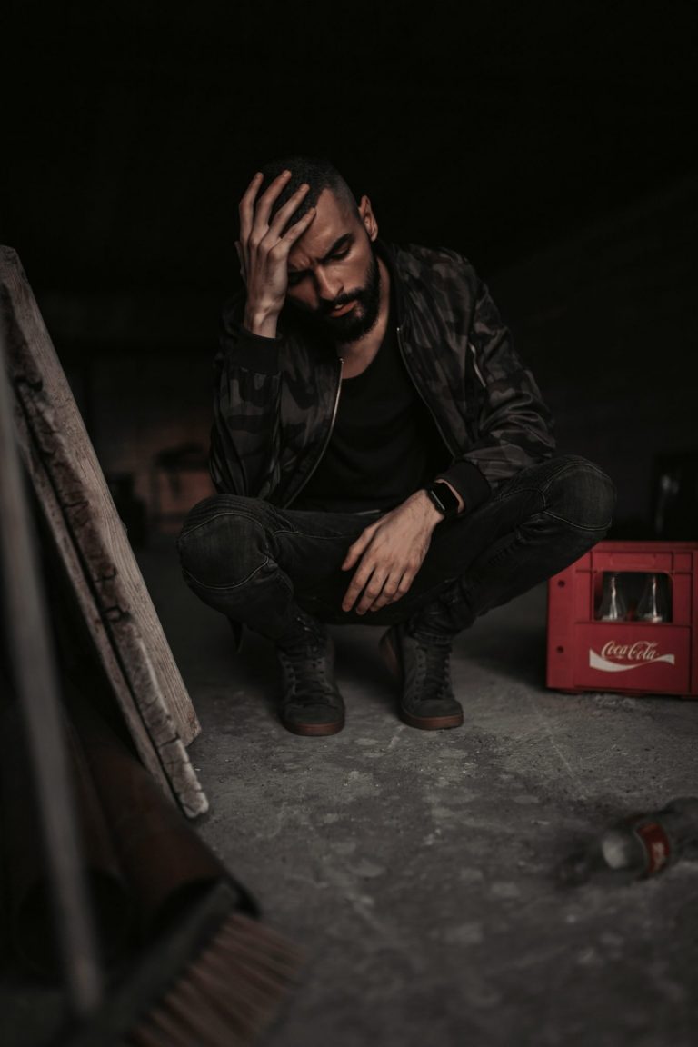 man crouching on floor holding his head