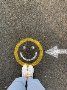 person in white shoes standing by drawing of smiley face
