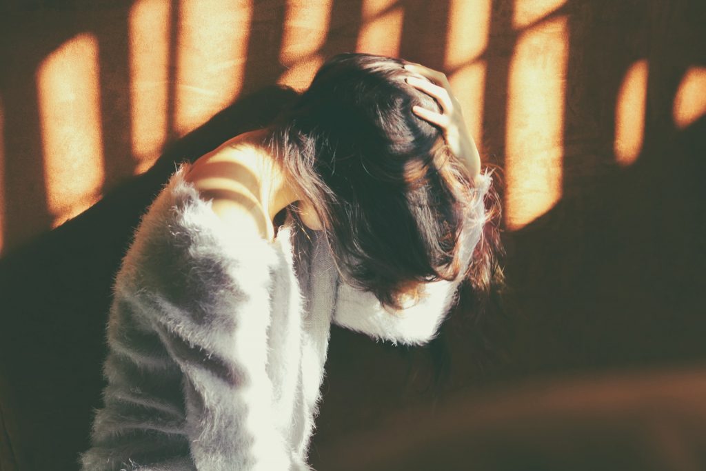 person with hair over face in a sunbeam