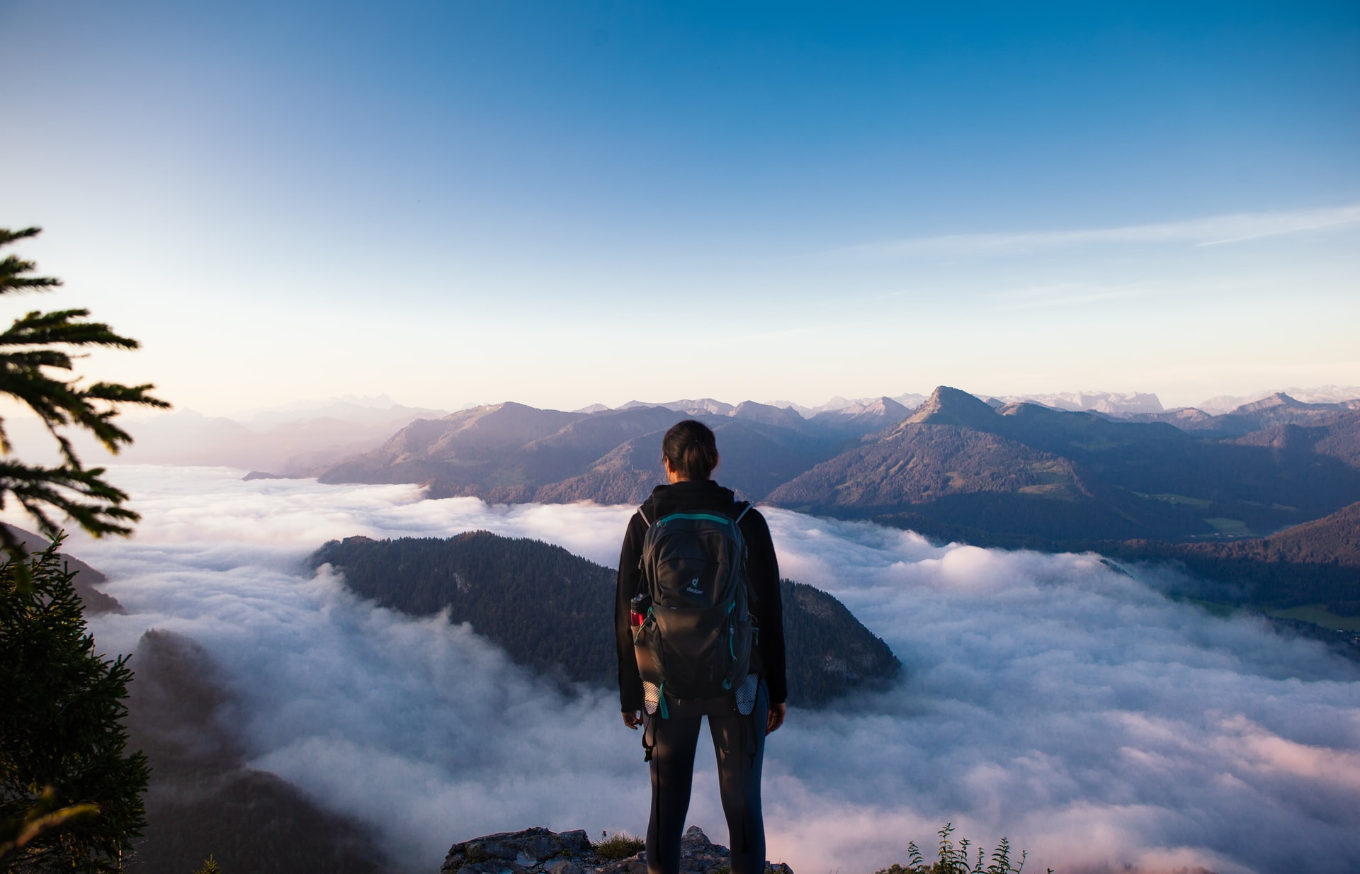 person on mountain overlooking cloudy valley