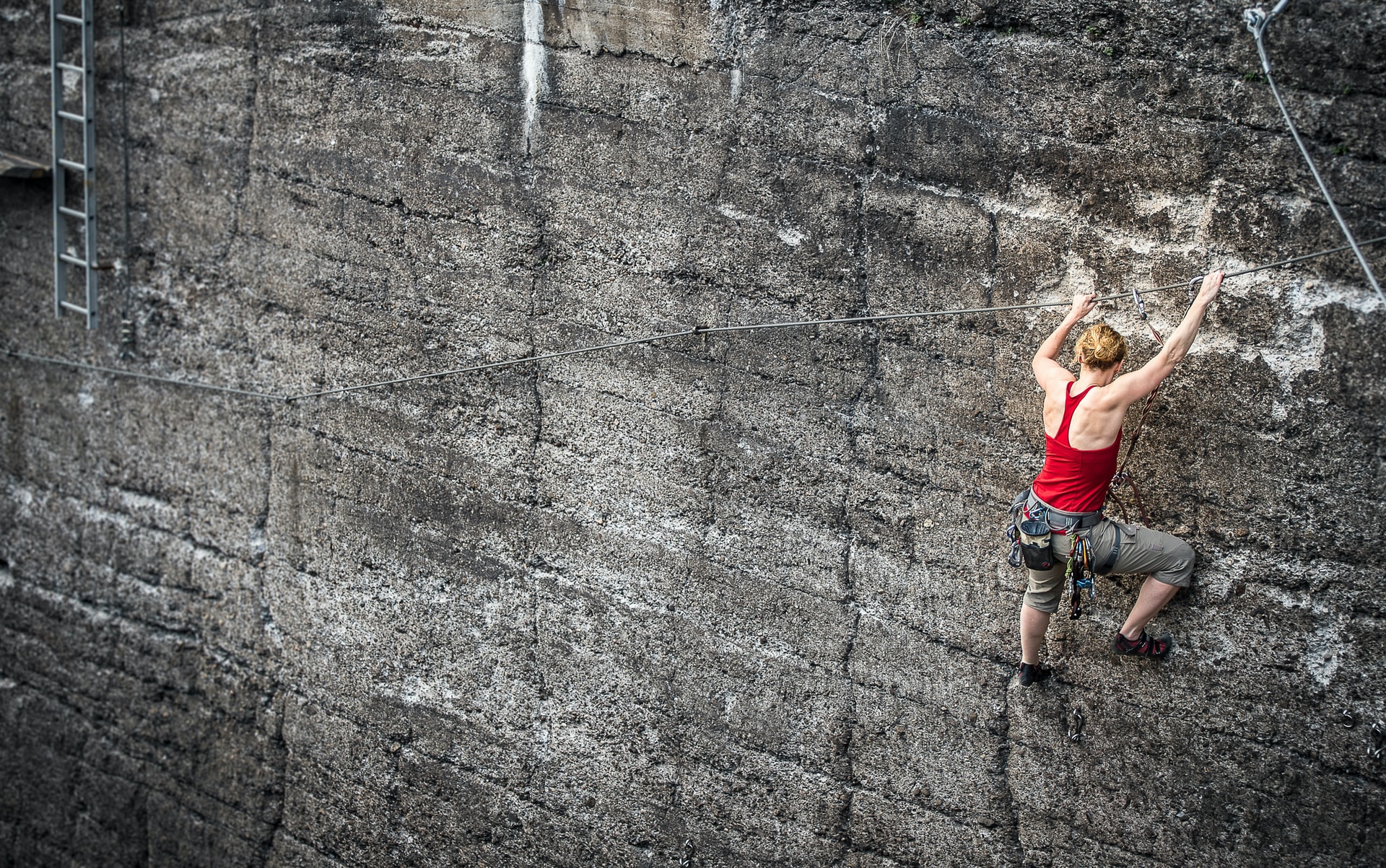 woman with climbing gear scaling a gray wall