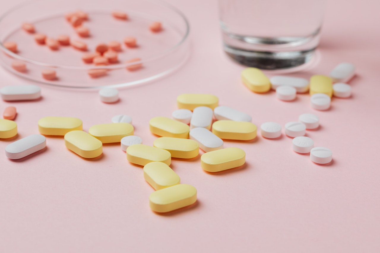 pills and glasses on a pink table