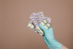 hand with medical glove holding prescription pill packets