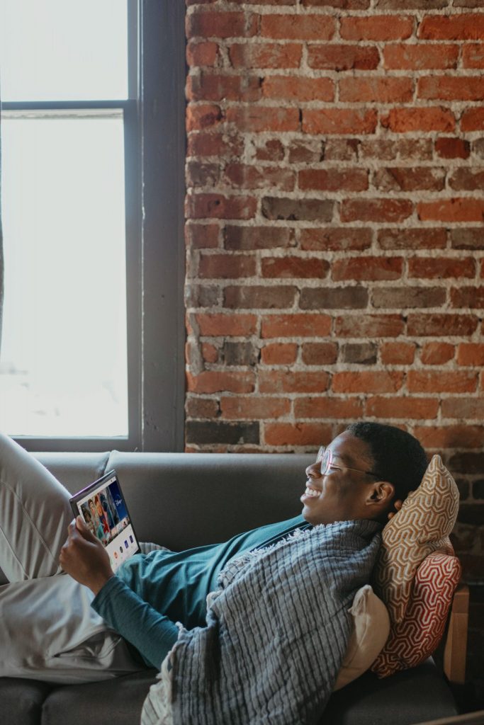 person relaxing on couch using a tablet