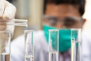 researcher pouring liquid into test tubes