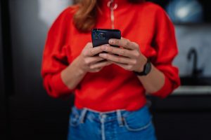 woman in red sweater swiping on smartphone app