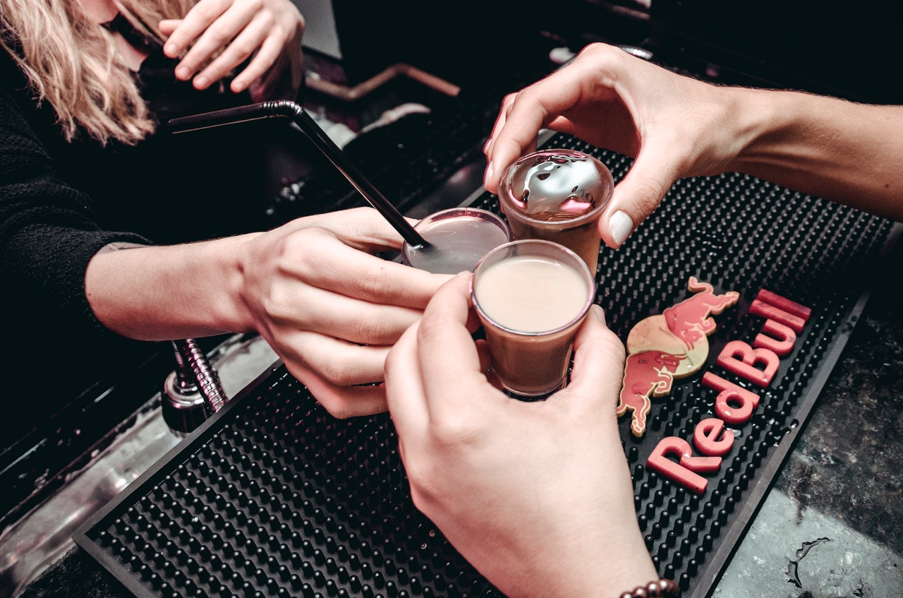 hands holding several shots at bar