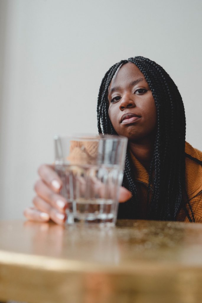 serious-looking woman holding a glass of water