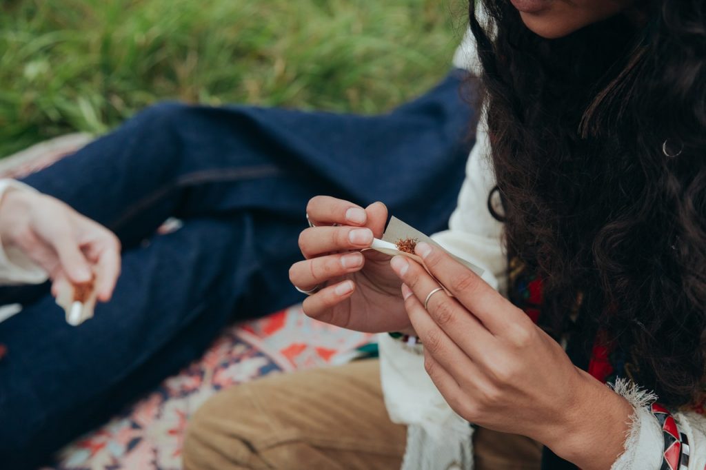 person rolling a cigarette sitting in the park