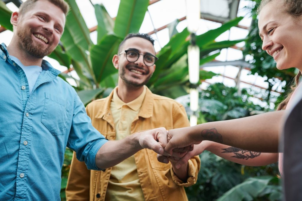 3 people smiling and doing a fist bump