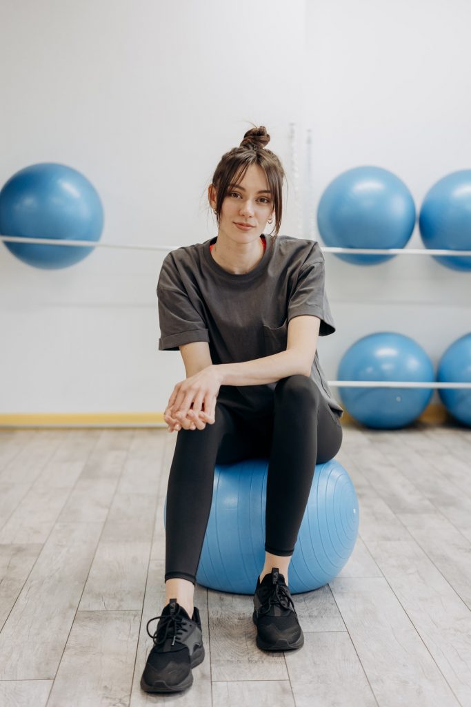 woman sitting on a blue yoga ball in a gym