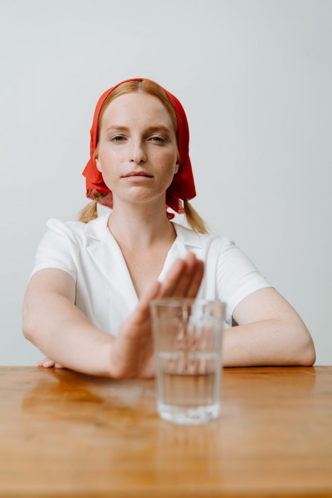 woman in white shirt pushing away glass