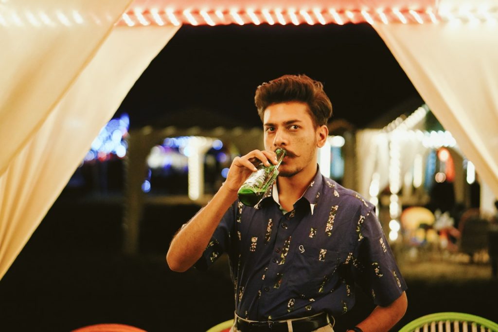 young serious looking man drinking a beer