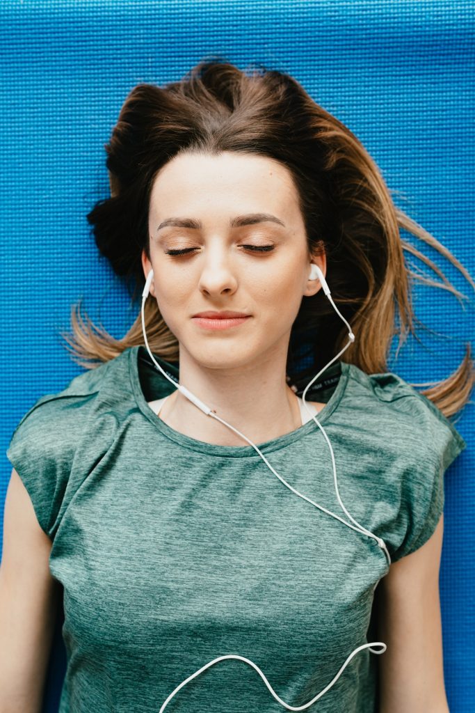 woman lying on yoga mat with headphones