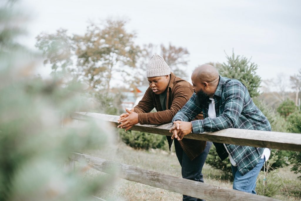 father talking to son leaning on fence