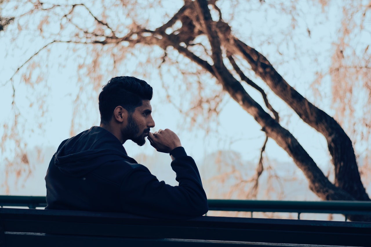 somber looking man sitting on bench