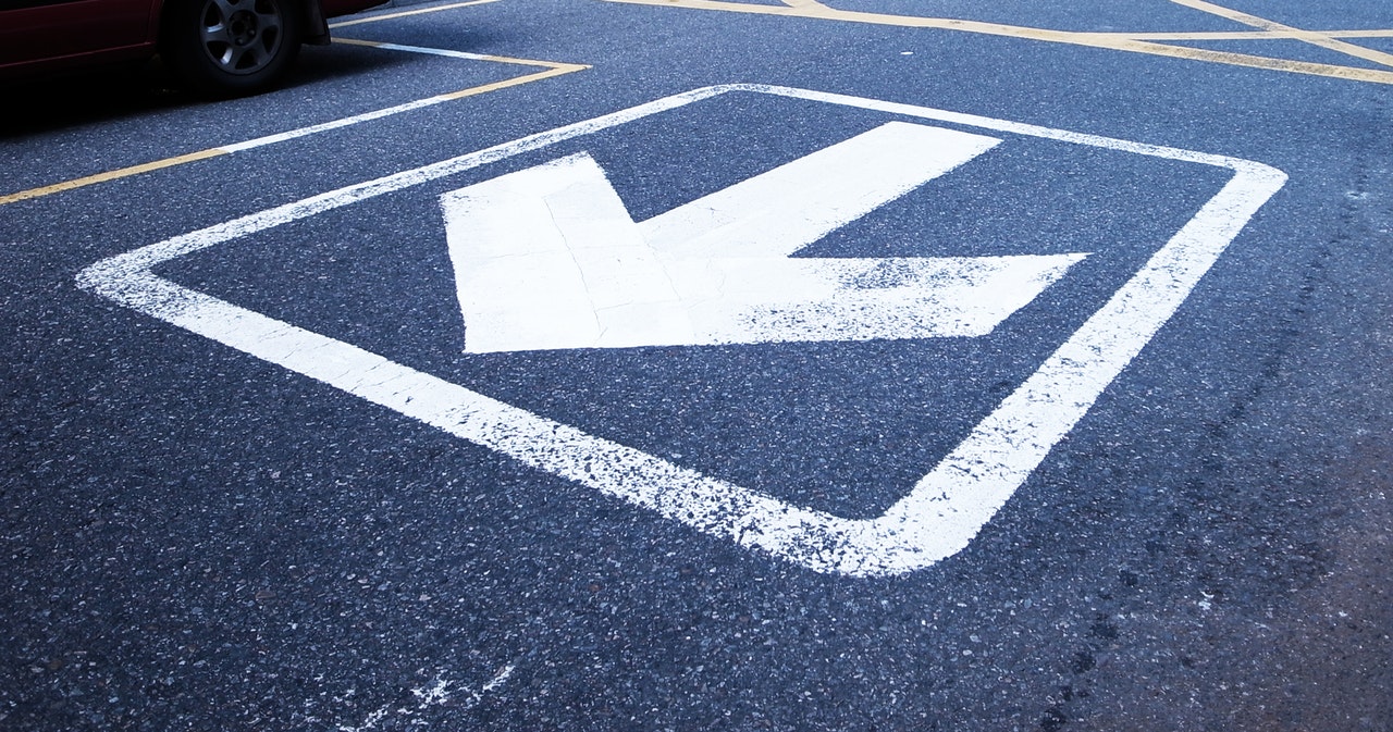 large white turning arrow on black pavement