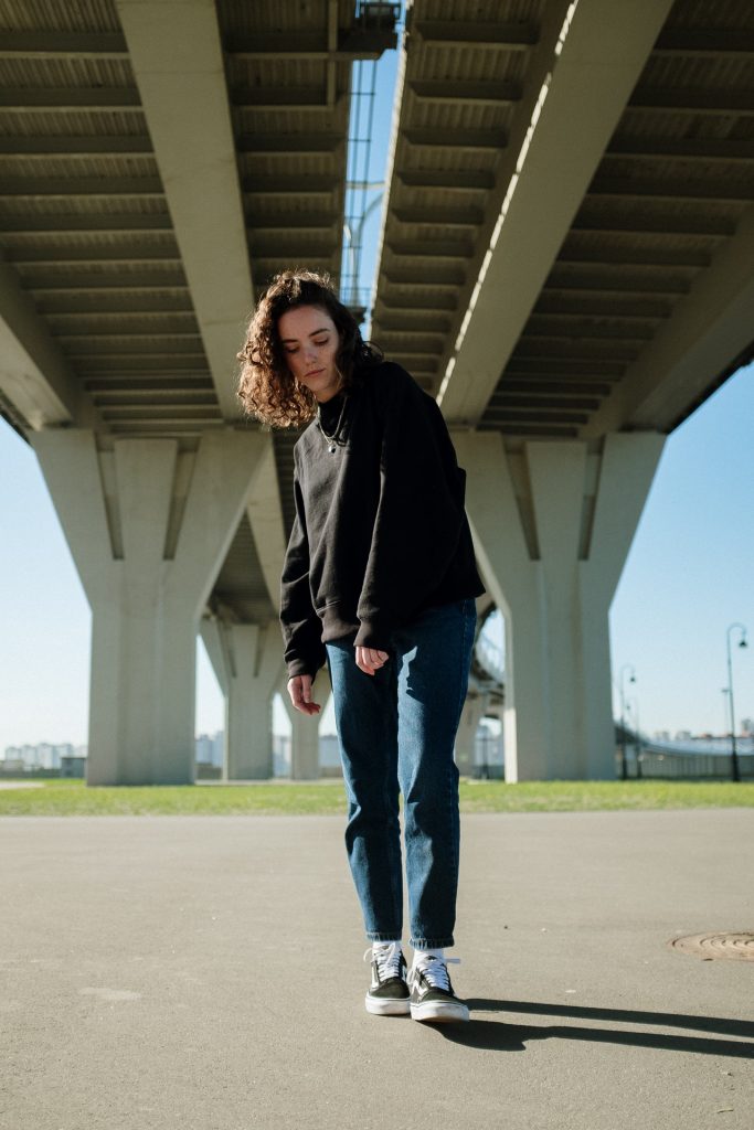 young woman in black jacket under overpass