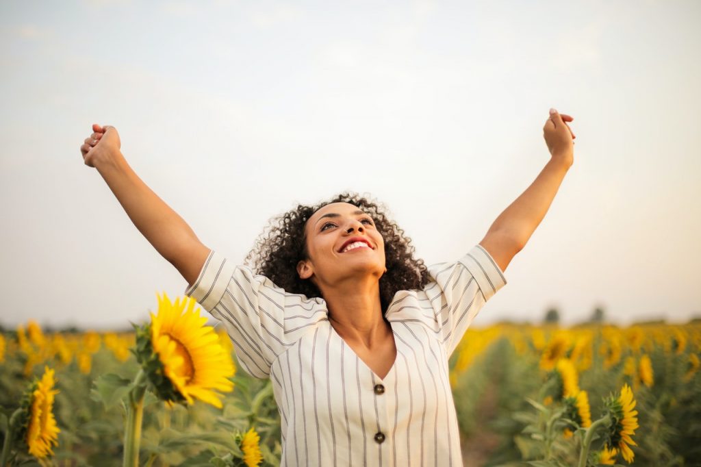 smiling woman looking upward with arms outstretched