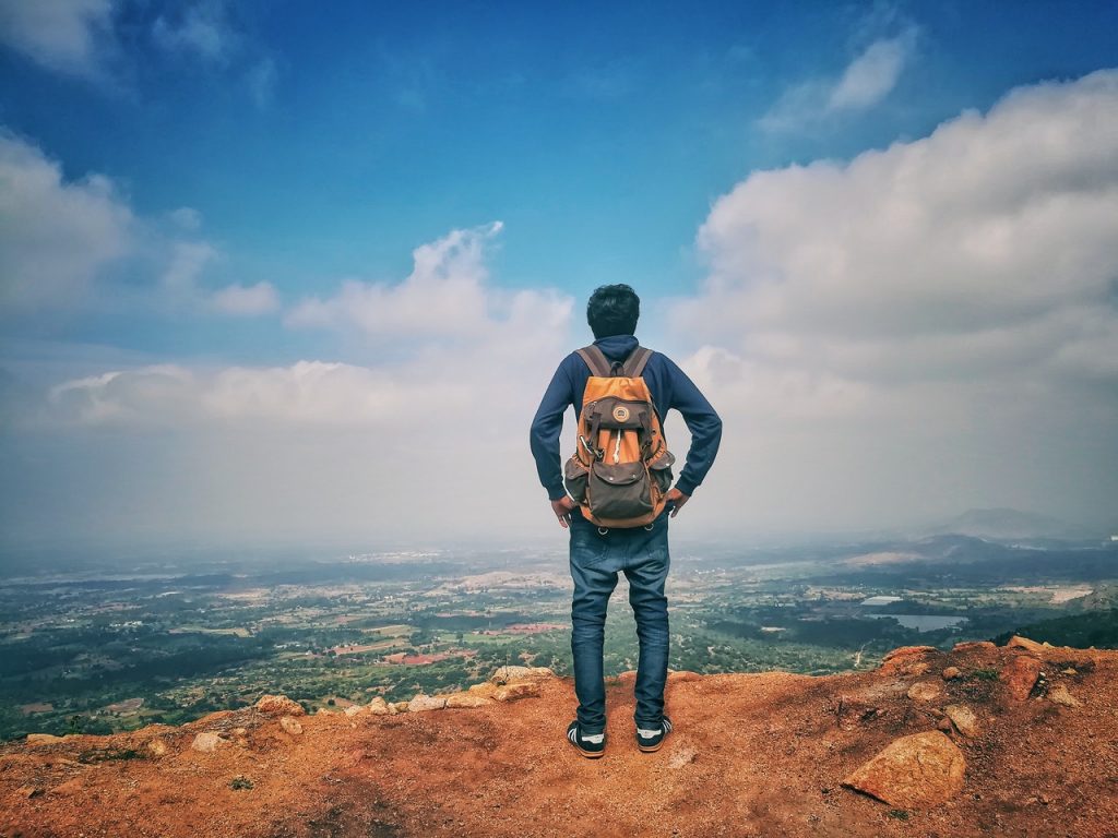 man overlooking blue horizon from hilltop
