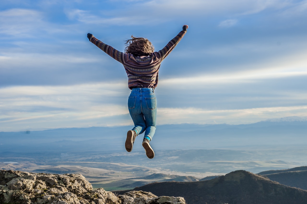 woman jumping ecstatically over landscape