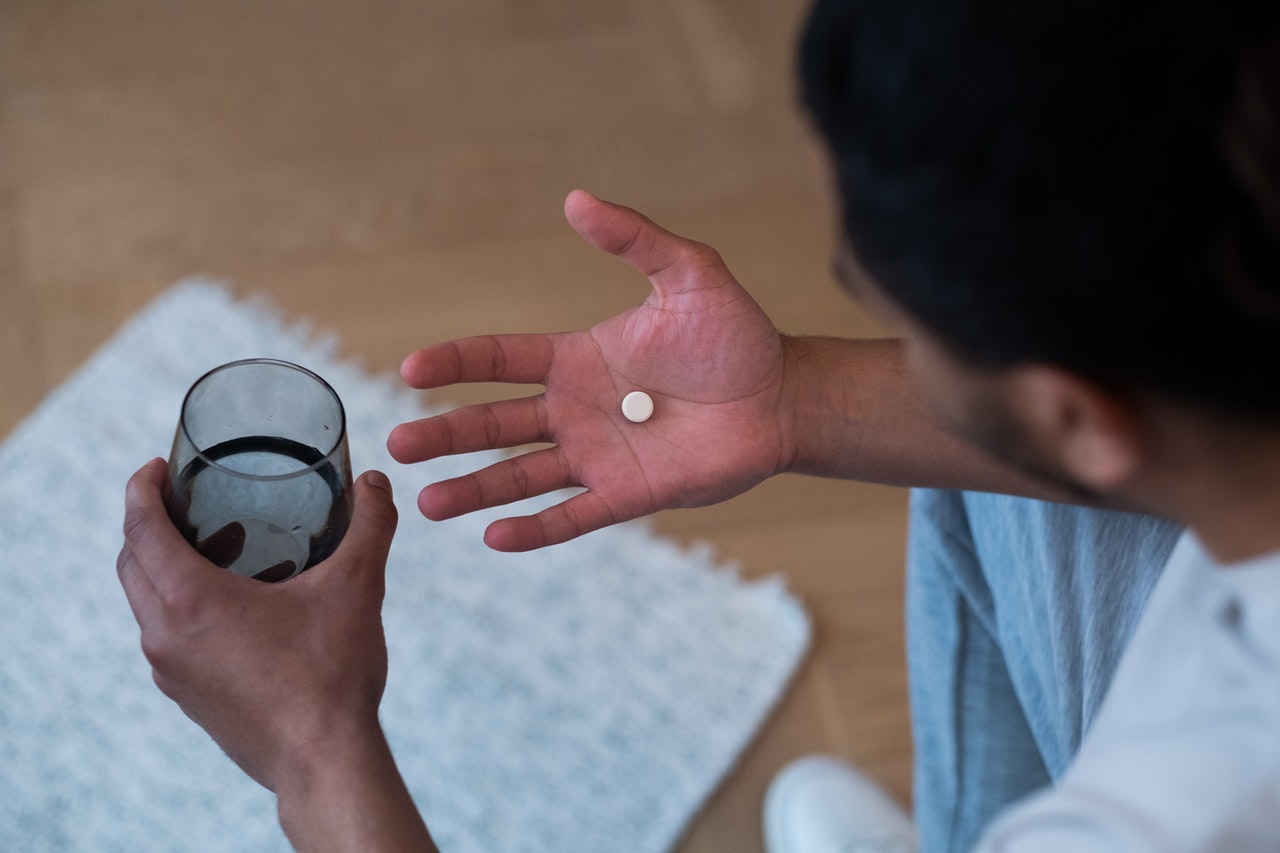 man taking a pill with glass of water