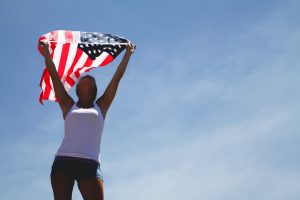 woman holding american flag against sky background