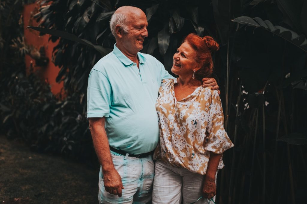 older couple standing outdoors smiling at each other