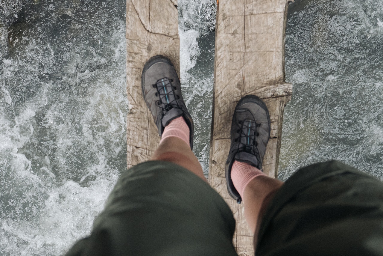 two fee crossing a river on two logs