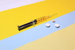 syringe and pills on blue and yellow background