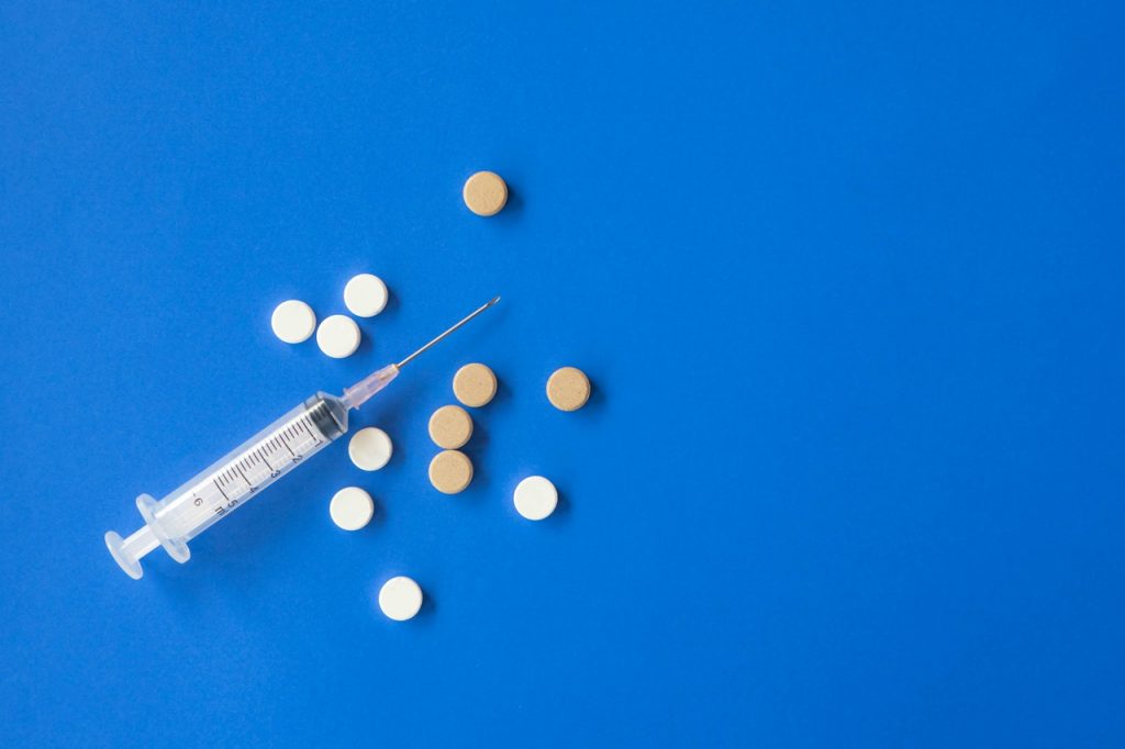 syringe and pills on blue background