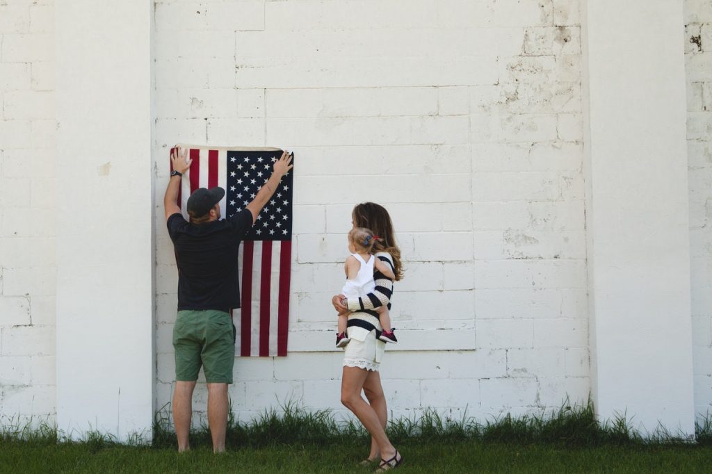 man putting flag on wall with mother and child